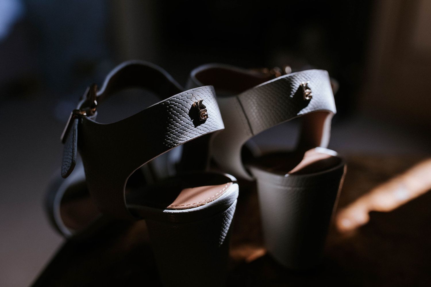 Close-up of elegant black dress shoes with textured detail in moody lighting.