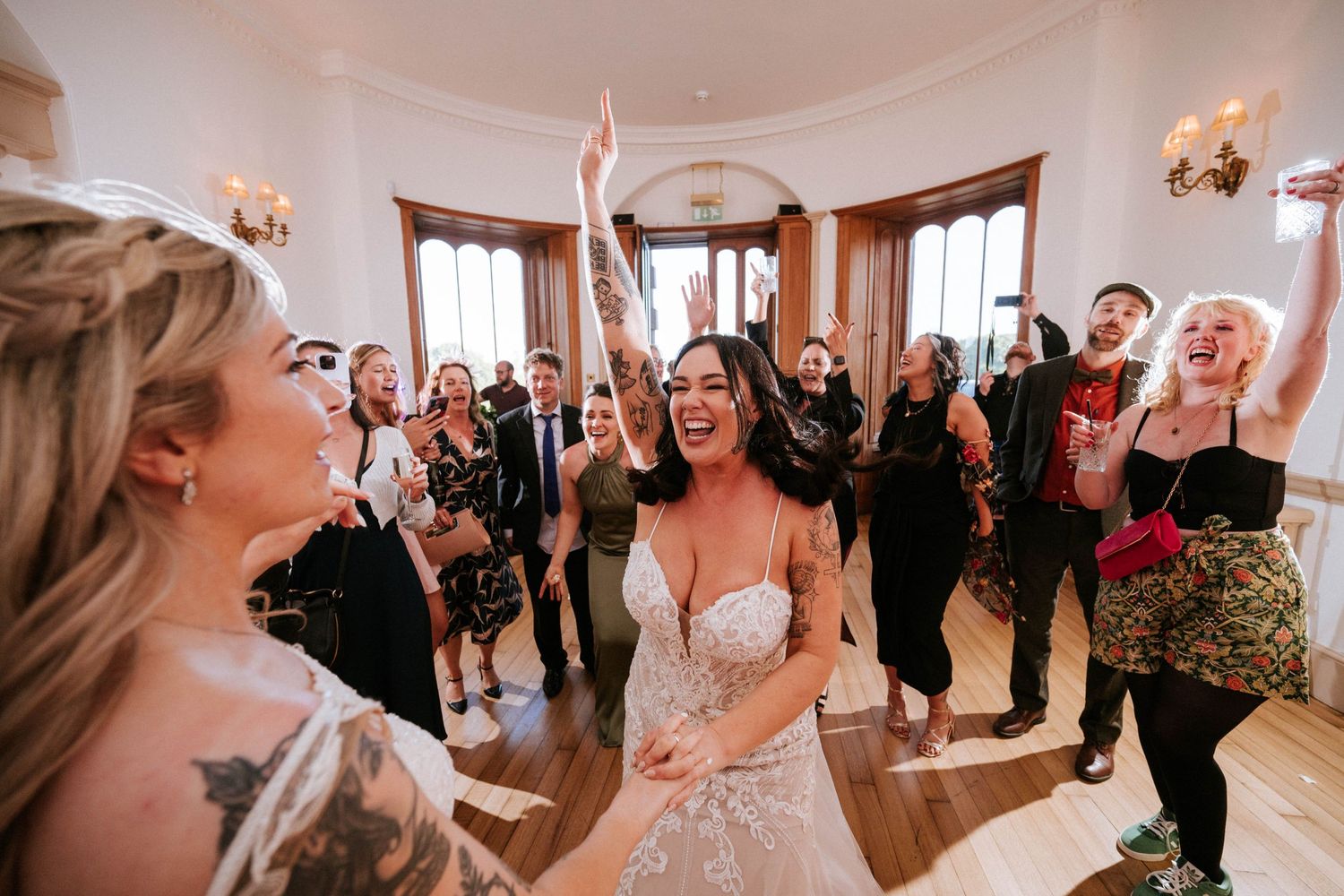 Fasque Castle Wedding Photography. Guests celebrate on a dance floor in an elegant white-walled ballroom during a wedding reception.