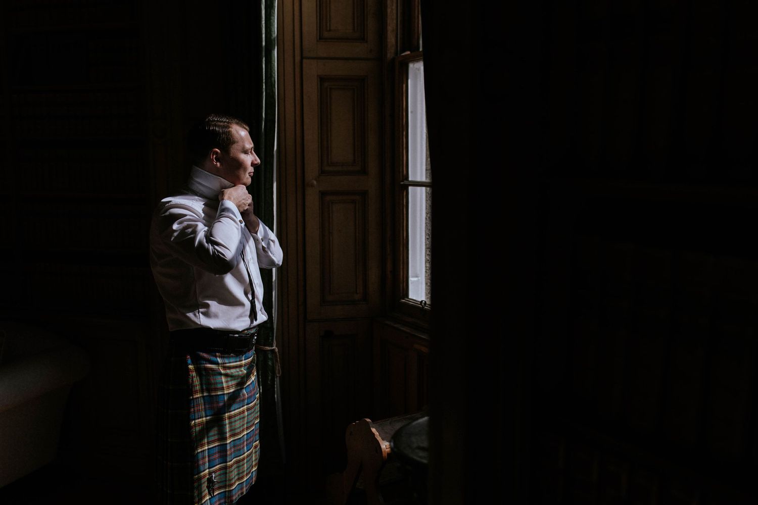 Groomsmen sharing laughter and drinks in a wood-paneled library before the wedding ceremony.