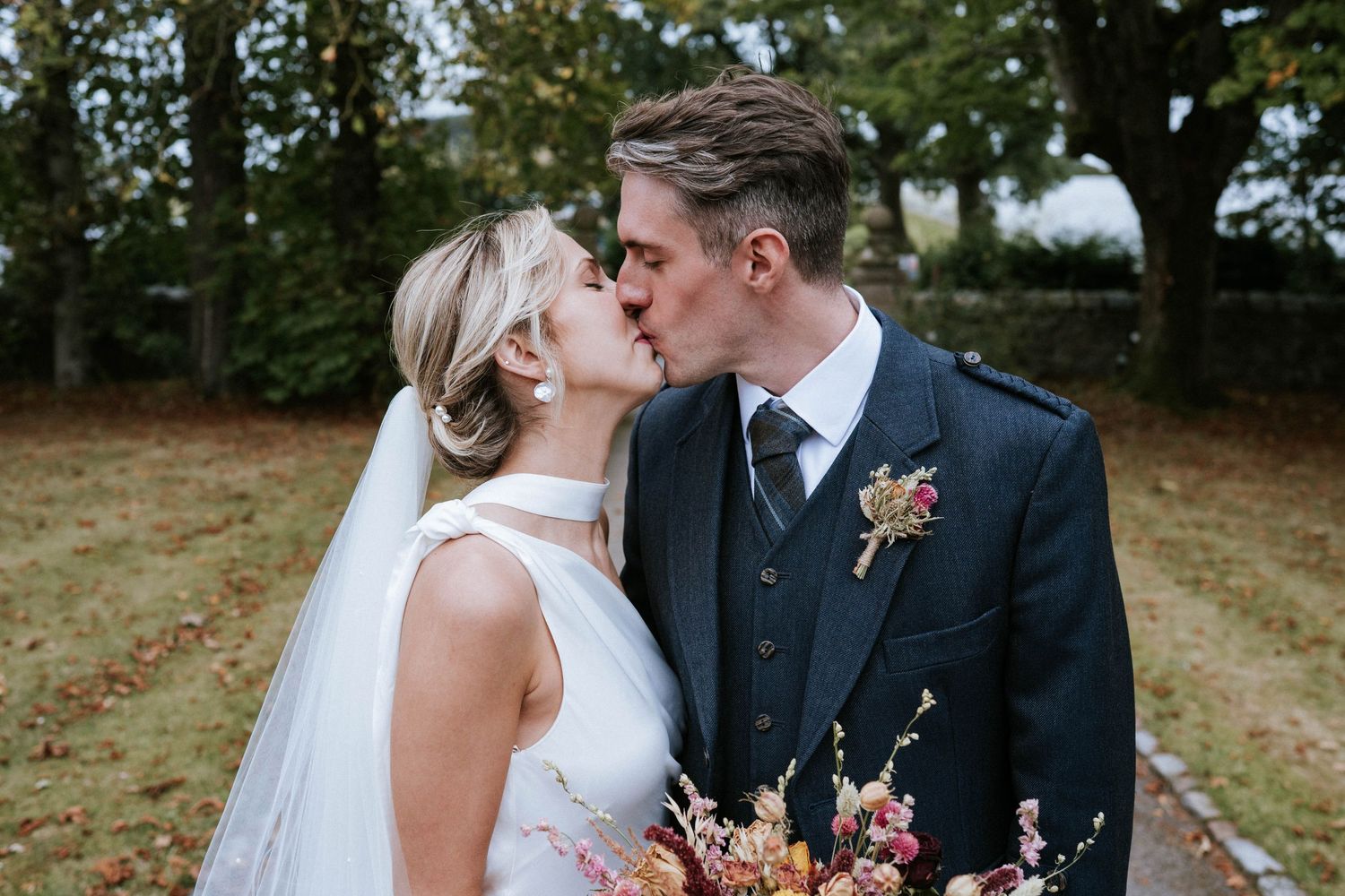 Intimate wedding portraits captured outdoors with autumn-colored floral bouquet details.