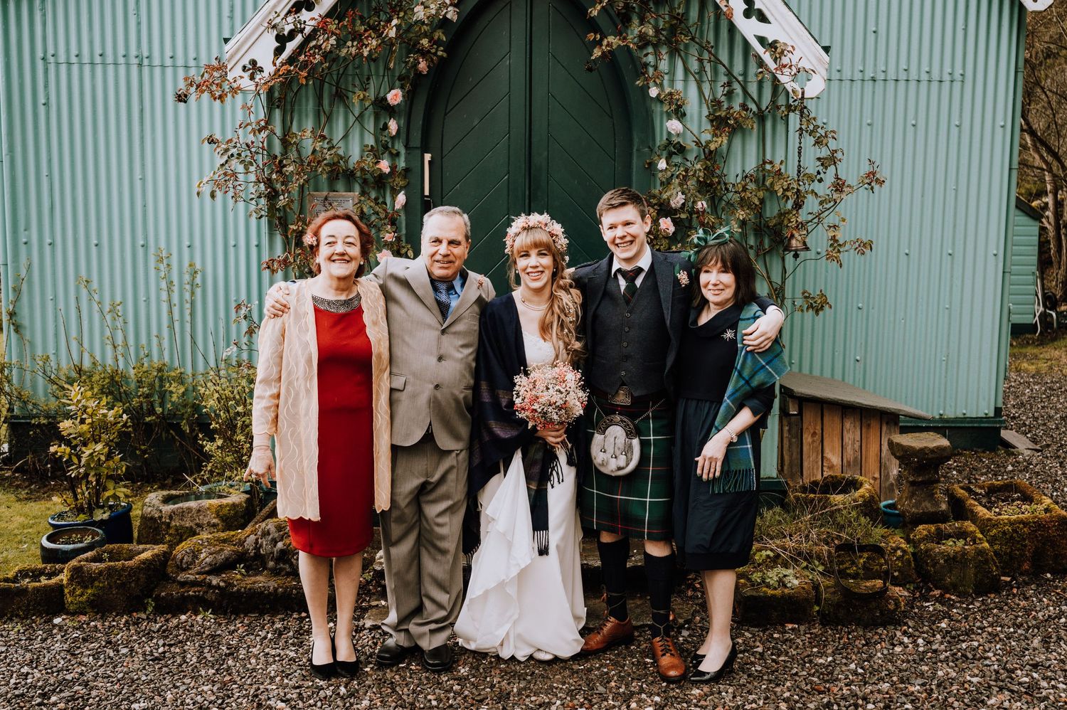 Wedding party poses by green church door with autumn vine decorations.