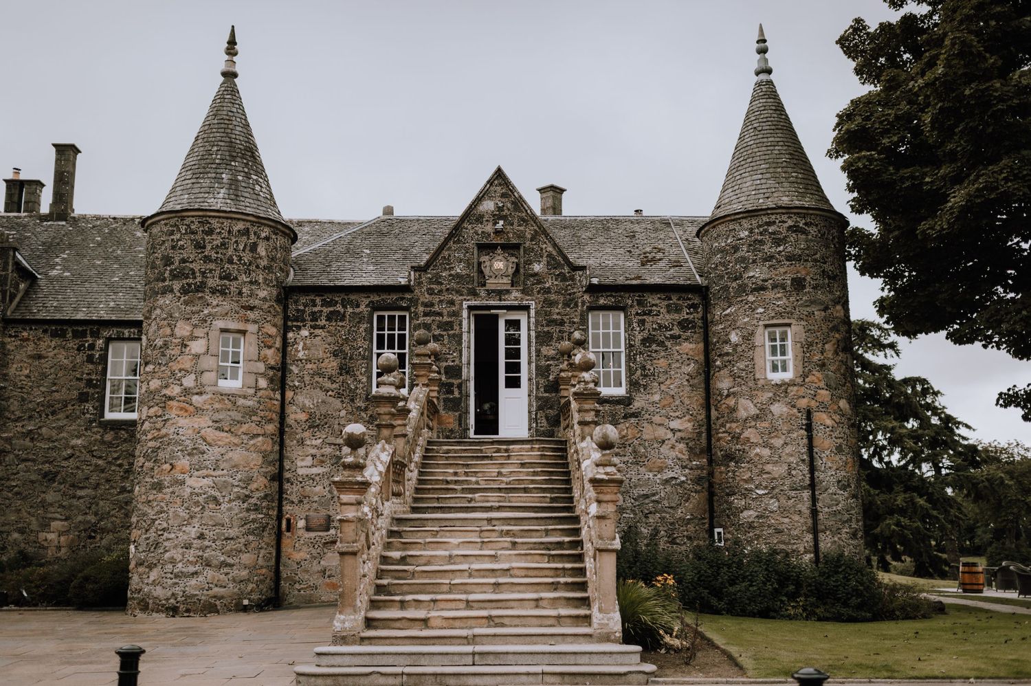 Stone castle entrance with grand staircase leading to front door between twin turrets.