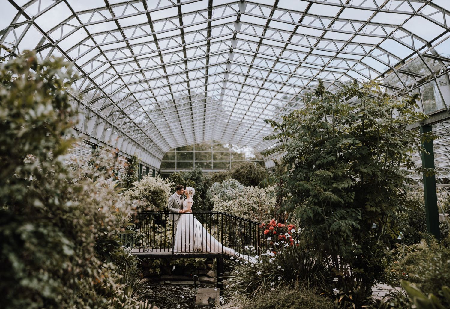 Interior view of a beautiful glass-domed conservatory with lush greenery and pathways.
