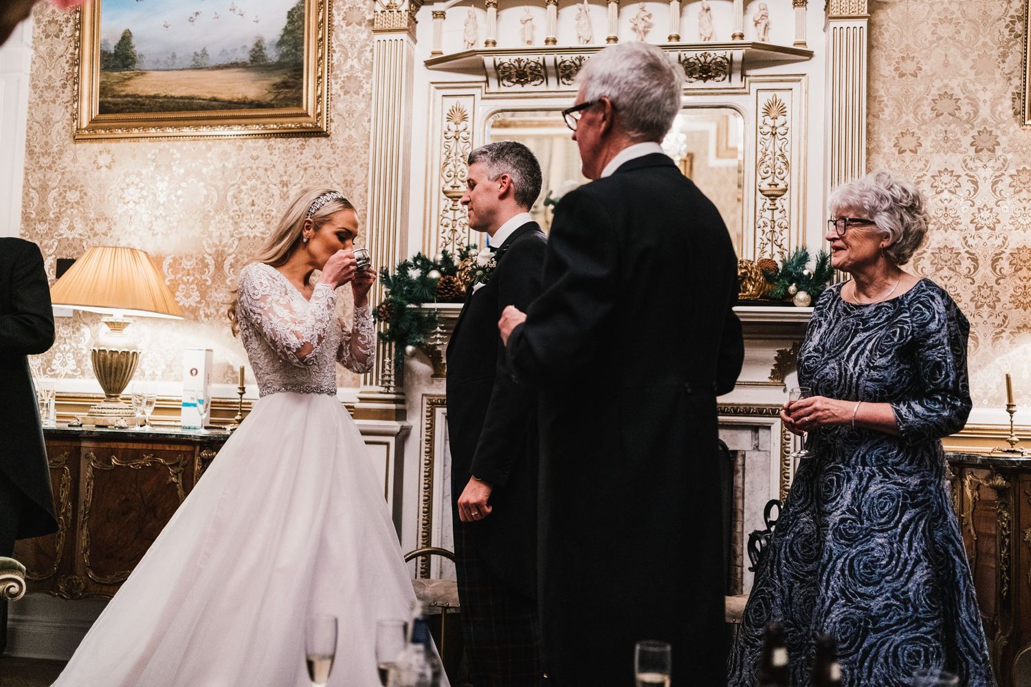 An intimate wedding ceremony unfolds in a luxurious room with classical decor and artwork.