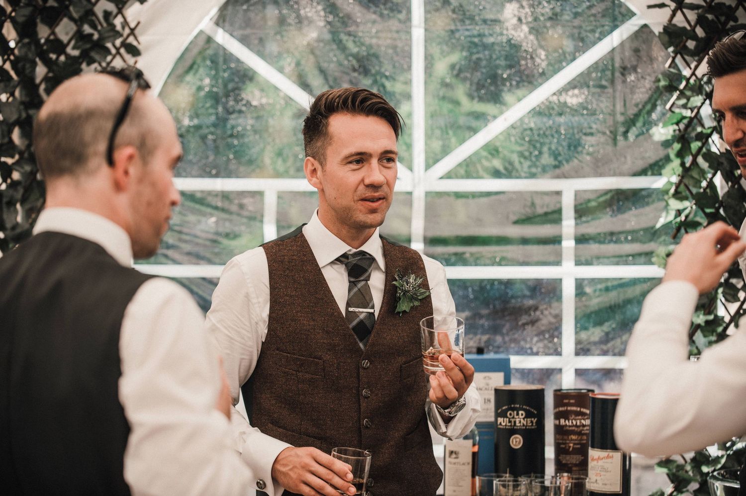 Guests enjoying drinks and conversation in an elegant greenhouse wedding reception setting.