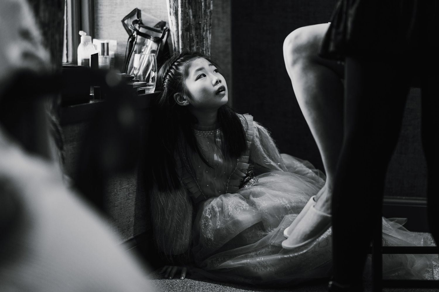 Candid black and white photo of wedding preparation activities on the floor.