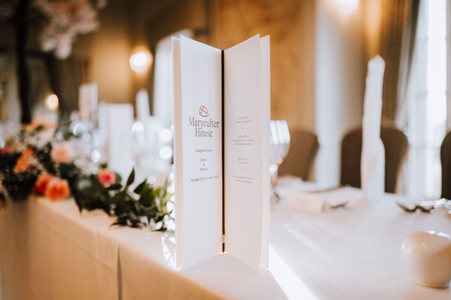 Elegant white menu cards stand upright on decorated wedding reception tables.