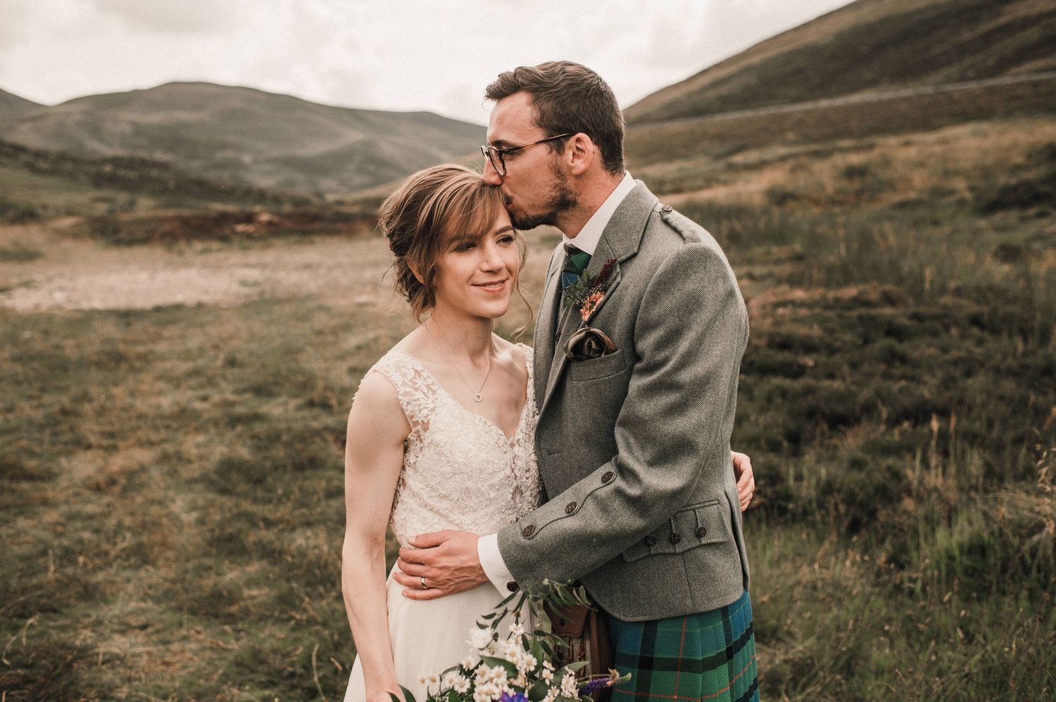 Intimate portrait of newlyweds embracing in Scottish Highland setting.