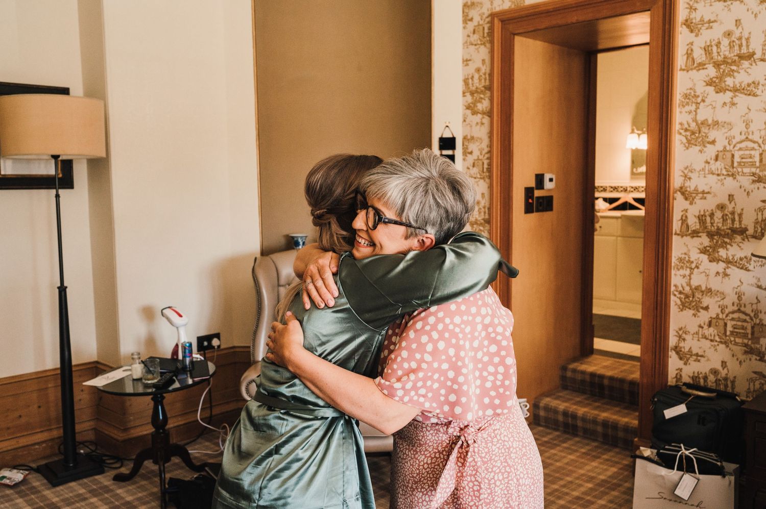 Two people sharing an emotional embrace in a warmly lit room with brick walls.