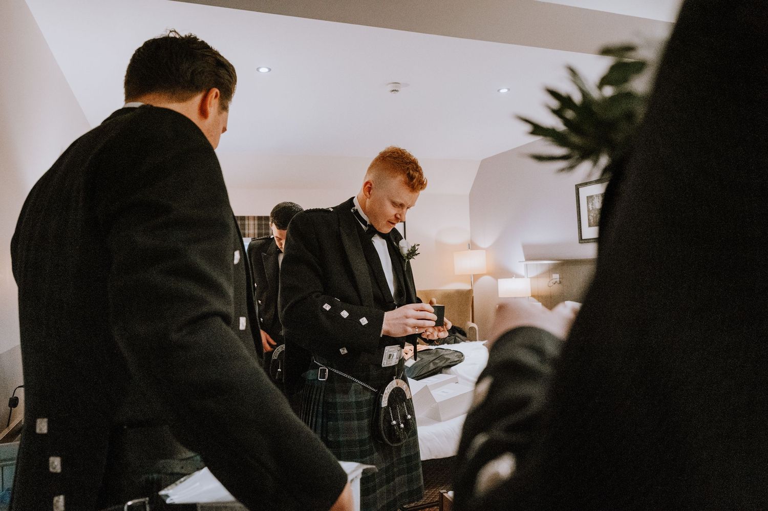 Wedding party members preparing in traditional Scottish formal attire.