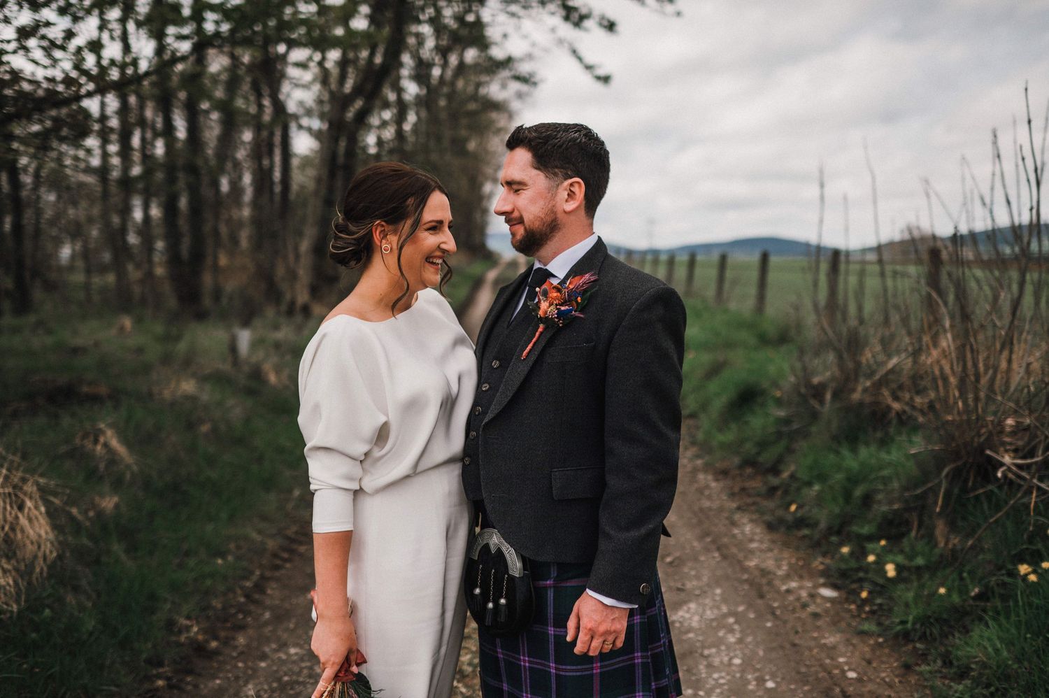 Scottish wedding couple sharing intimate moment on rural path.