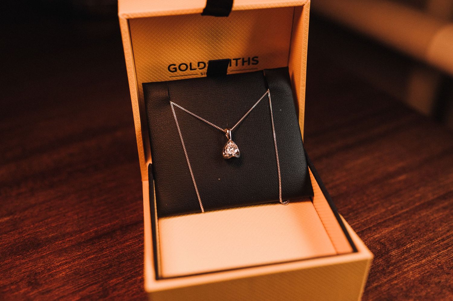 Delicate silver necklace with pendant displayed in an orange jewelry box.