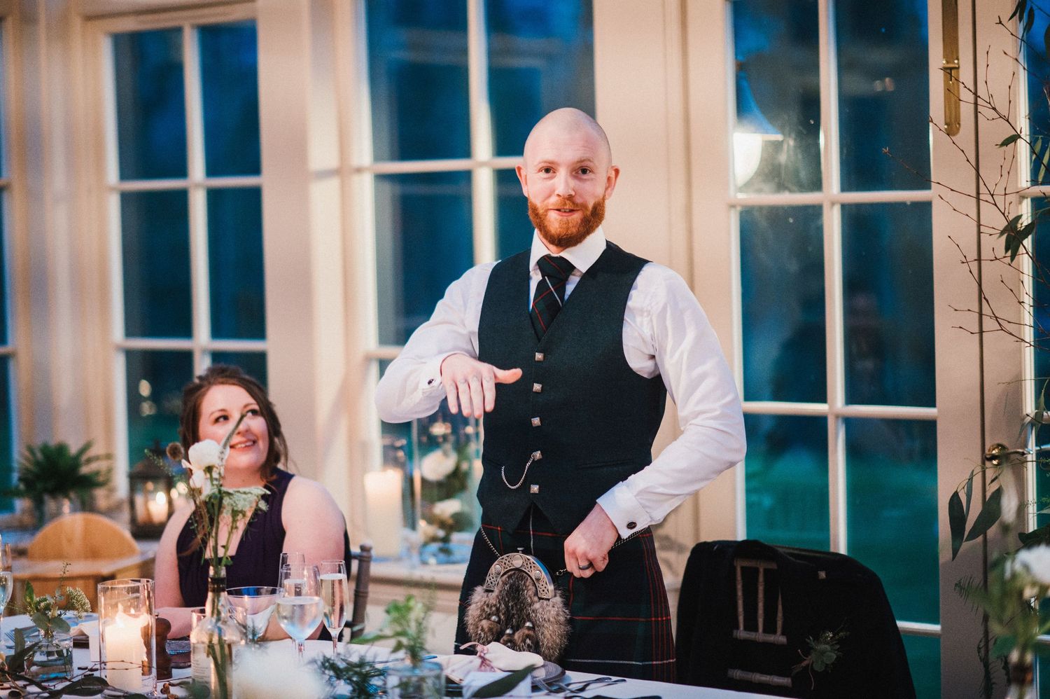 Wedding reception dining scene with formal table settings and candlelight.