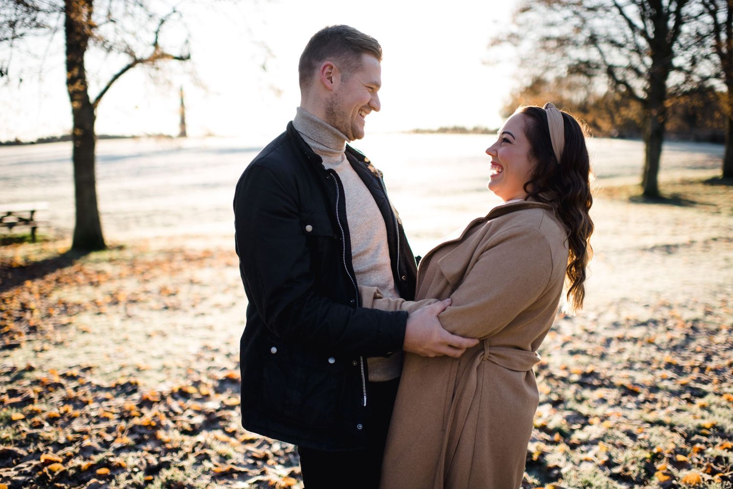 Couple sharing loving moment in park during golden hour autumn photoshoot.
