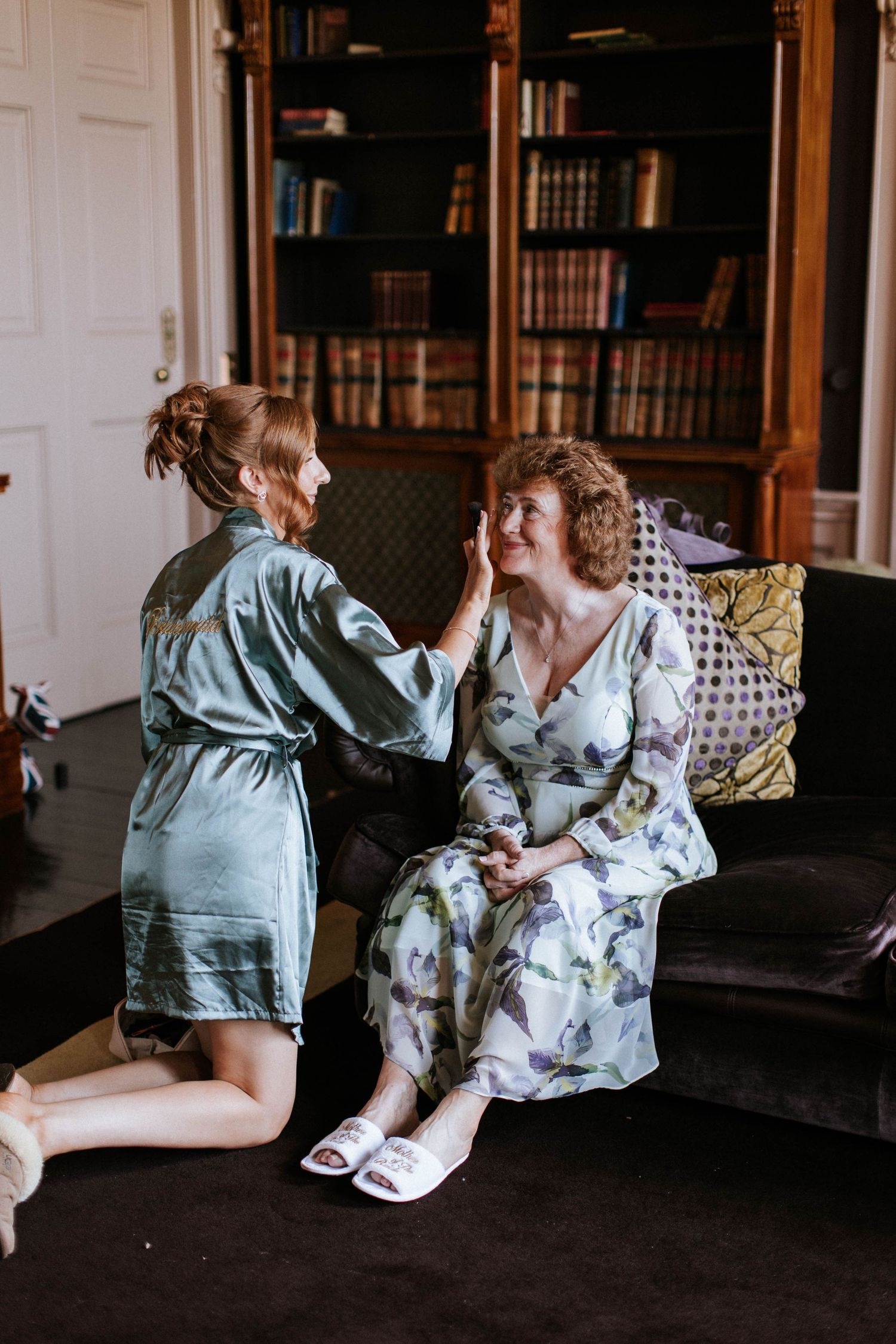 Wedding preparation moment in library room with dark bookshelves.