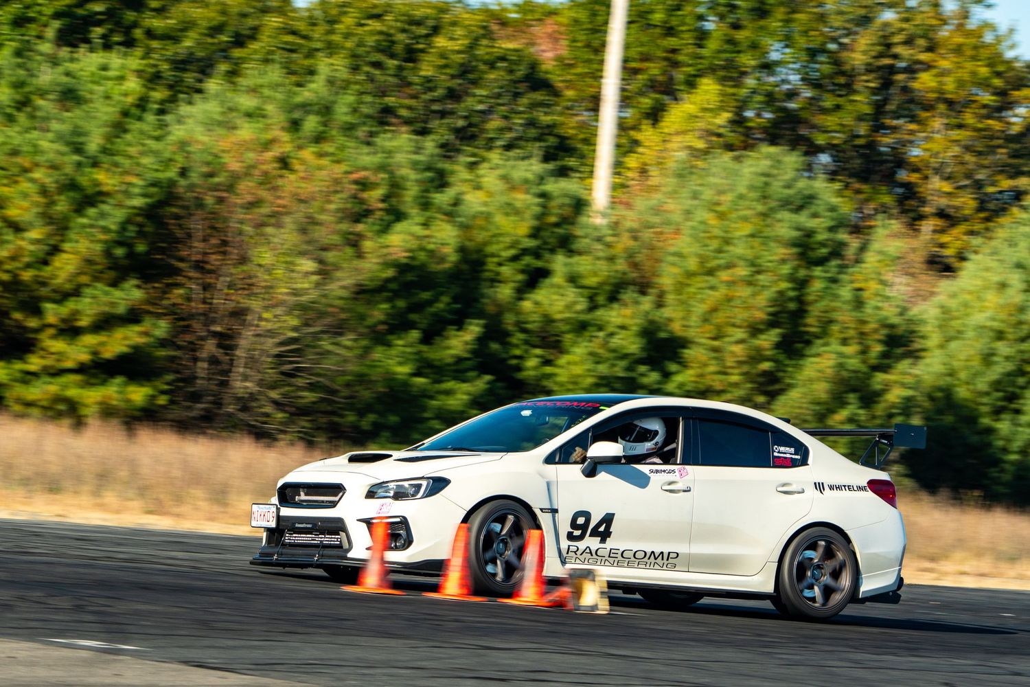 Sports cars competing on a race course with orange cones marking the track layout.