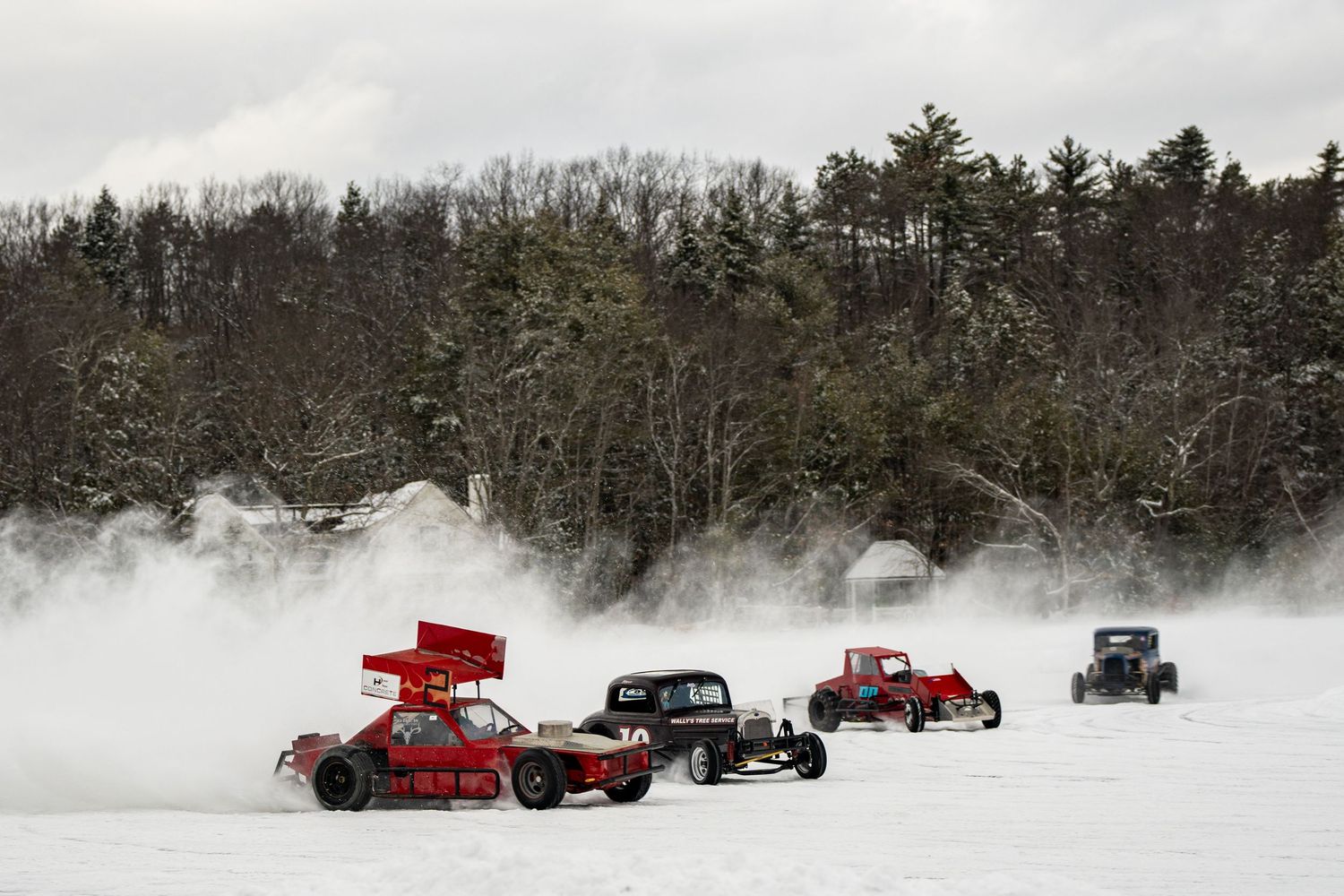 Vintage cars racing through deep snow on a winter rally course.