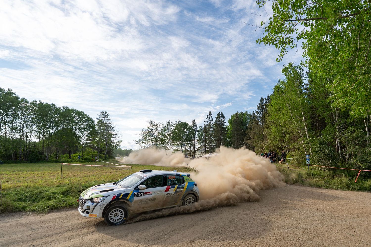 Rally cars power through dusty corners on a rural mountain course.