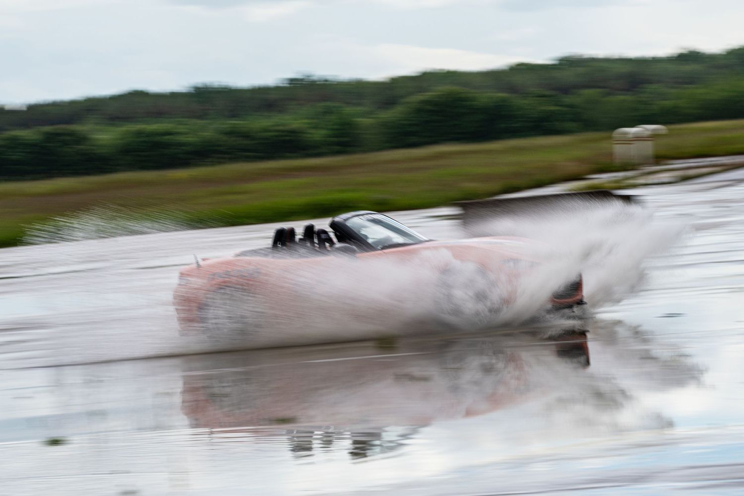 Race car creating dramatic water spray while speeding through a wet course.
