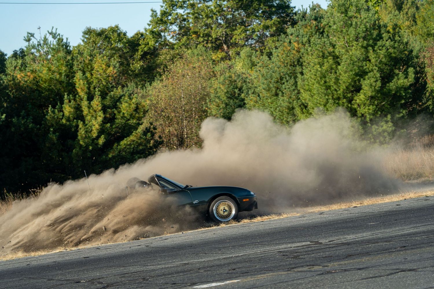 Race car kicking up dust while drifting on a dirt track.