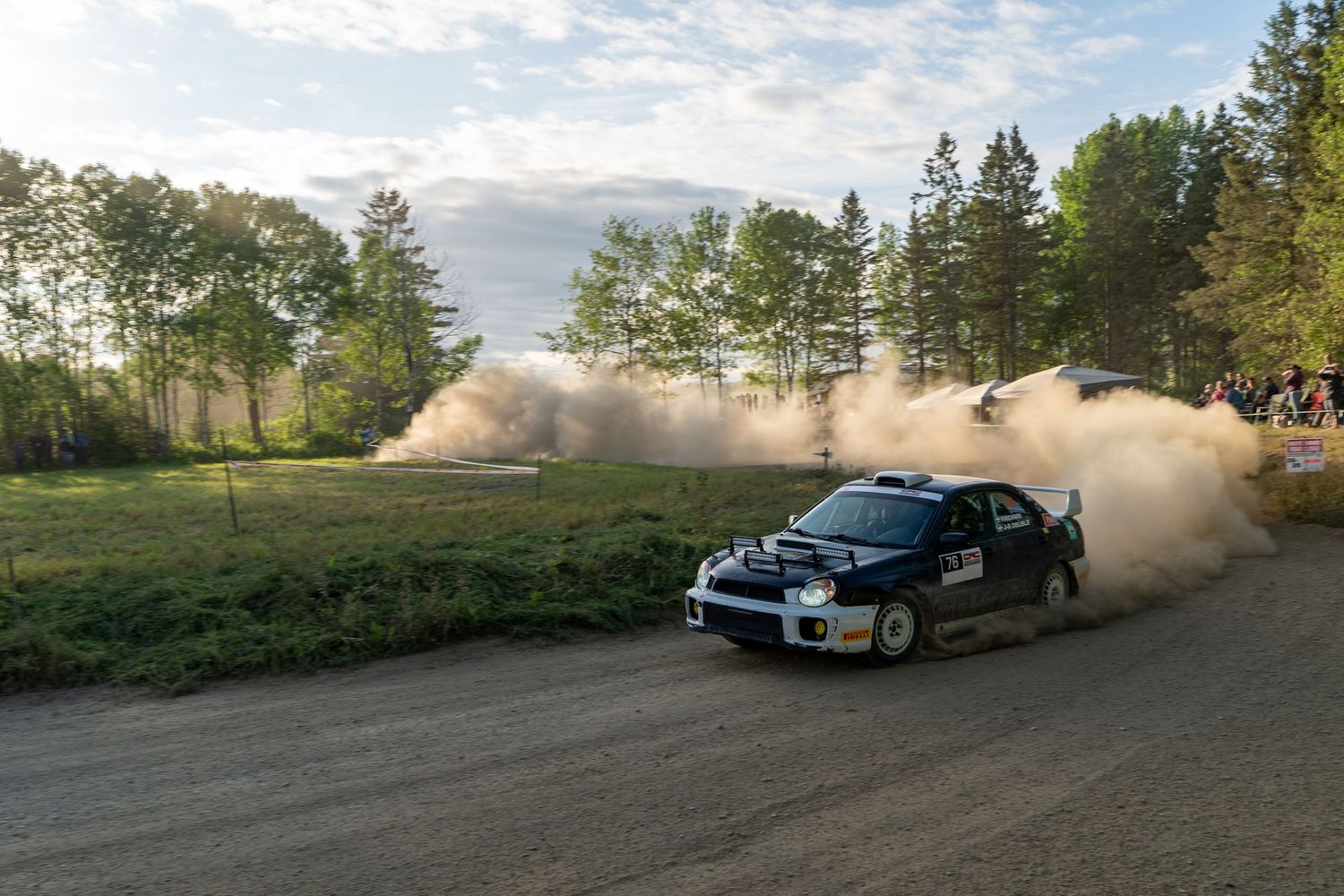 Rally cars race along scenic mountain roads creating dramatic dust clouds.