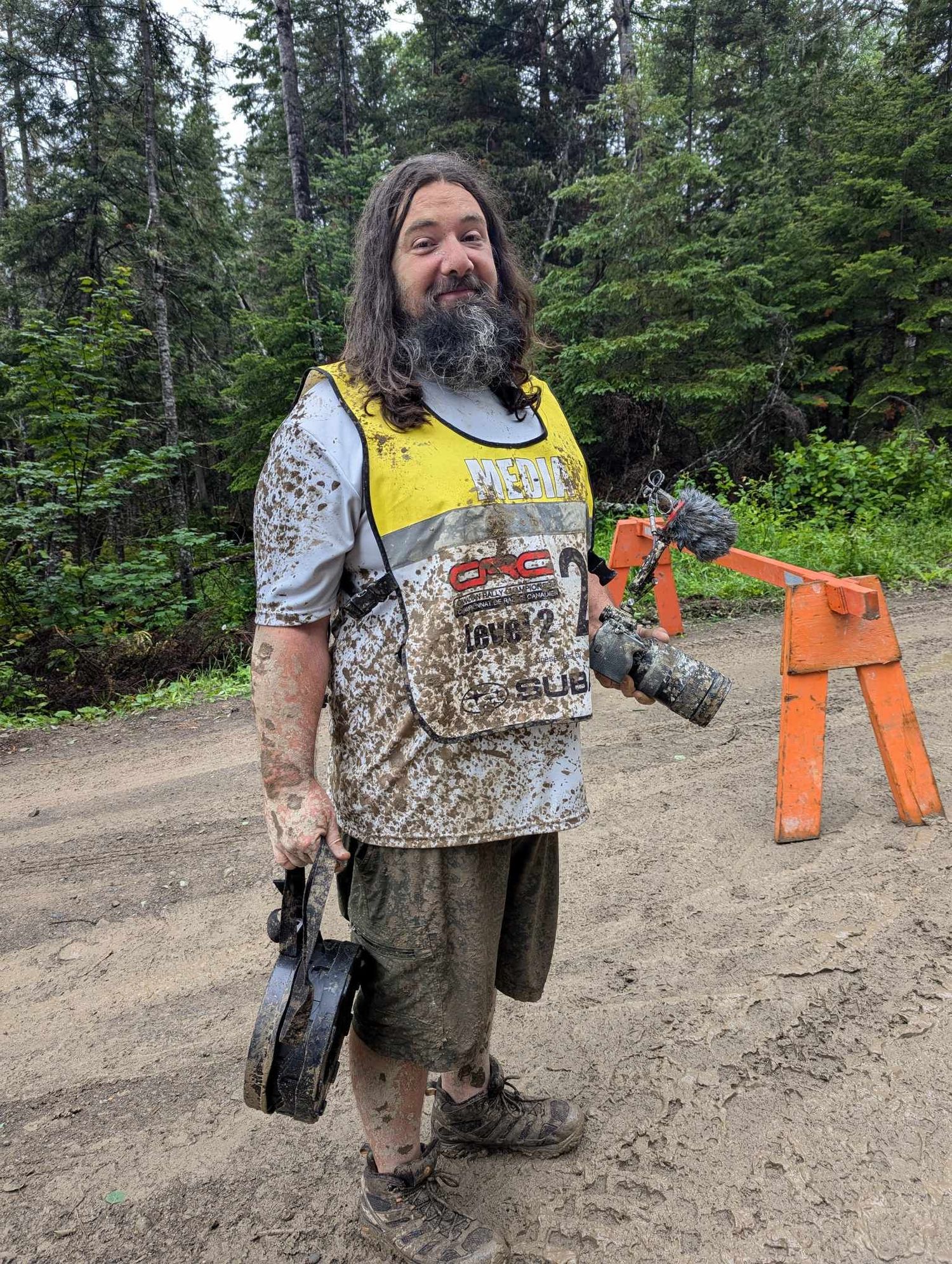 Chainsaw operator in safety gear working on trail maintenance in a forest setting.