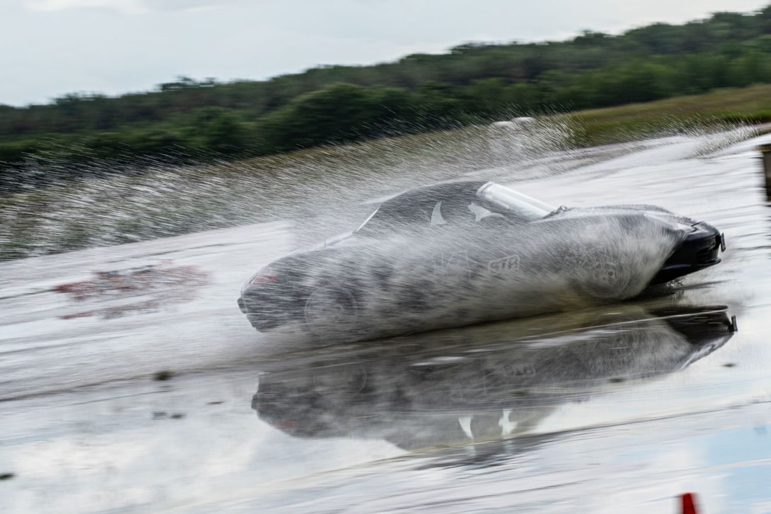 Race car creating dramatic rooster tail of water spray during high-speed run.
