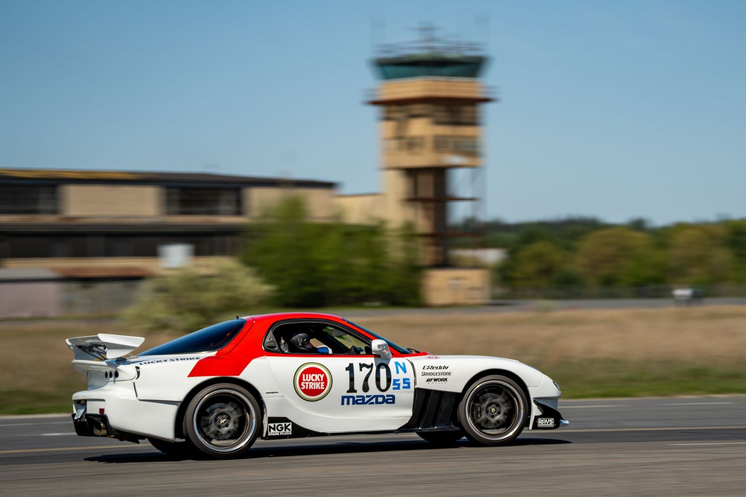 High-speed race cars blurring past on a sunny racetrack.