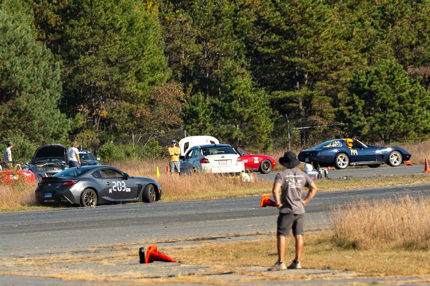Multiple cars navigating through an outdoor autocross course on a sunny day.