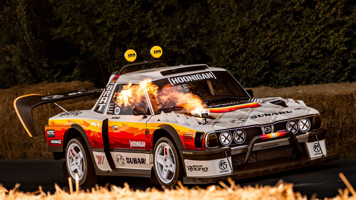 A rally car with flames shooting from exhaust pipes at Goodwood Festival of Speed hillclimb event.