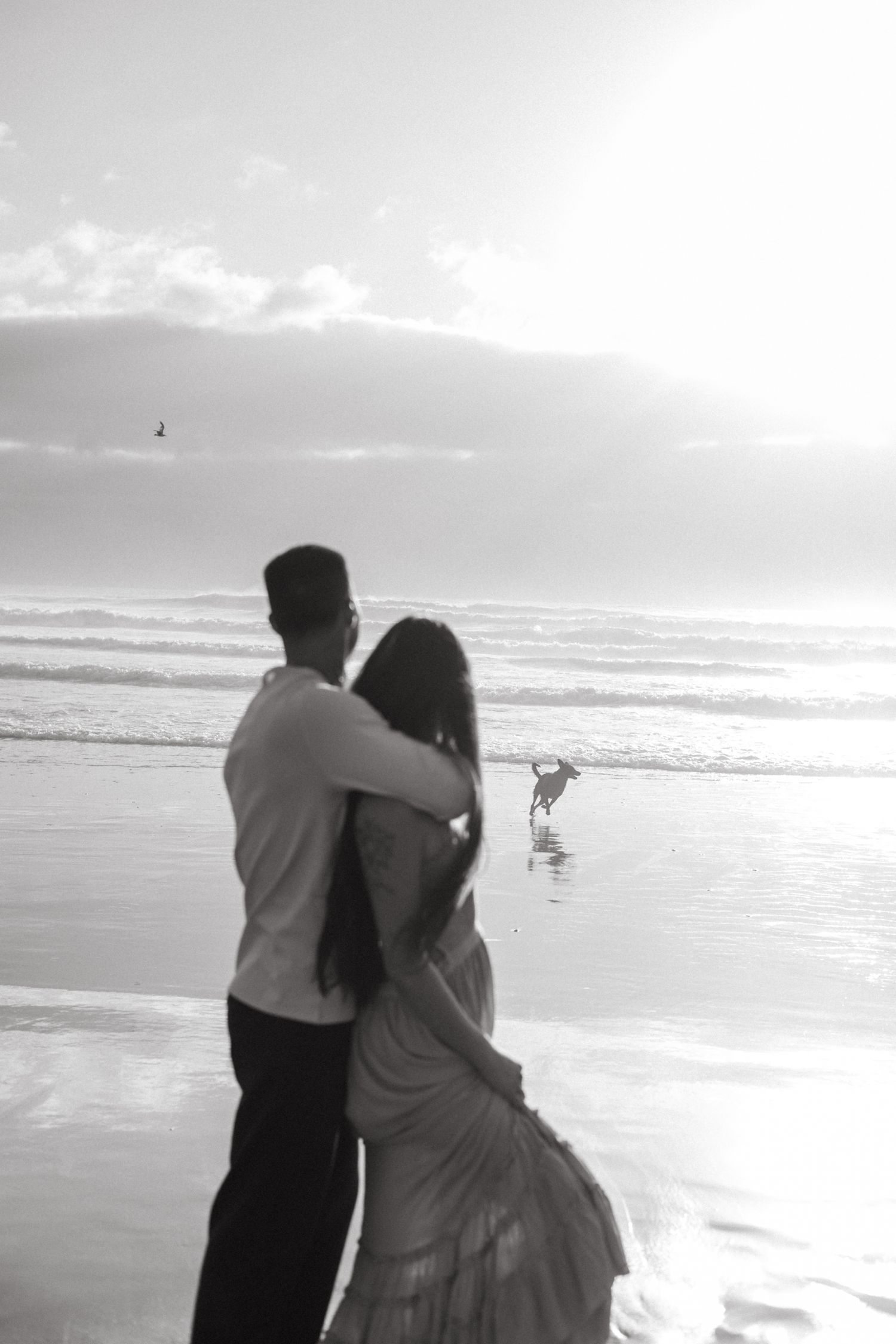 Couples candid beach session with Oregon Wedding photographer Andi and their dog running into ocean