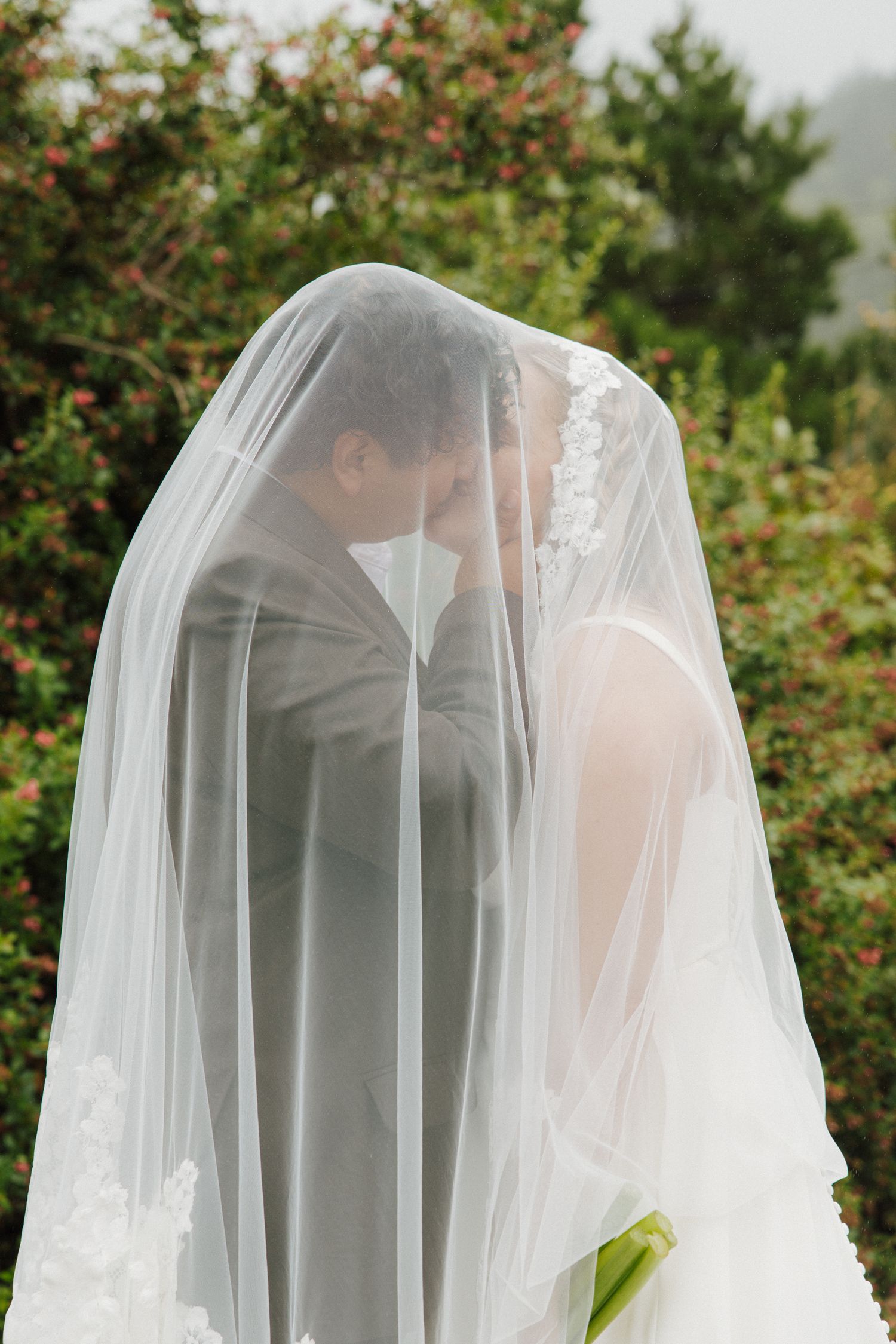 Wedding veil shot of PNW couple on wedding day kissing underneath veil together for dreamy, cinematic wedding shot