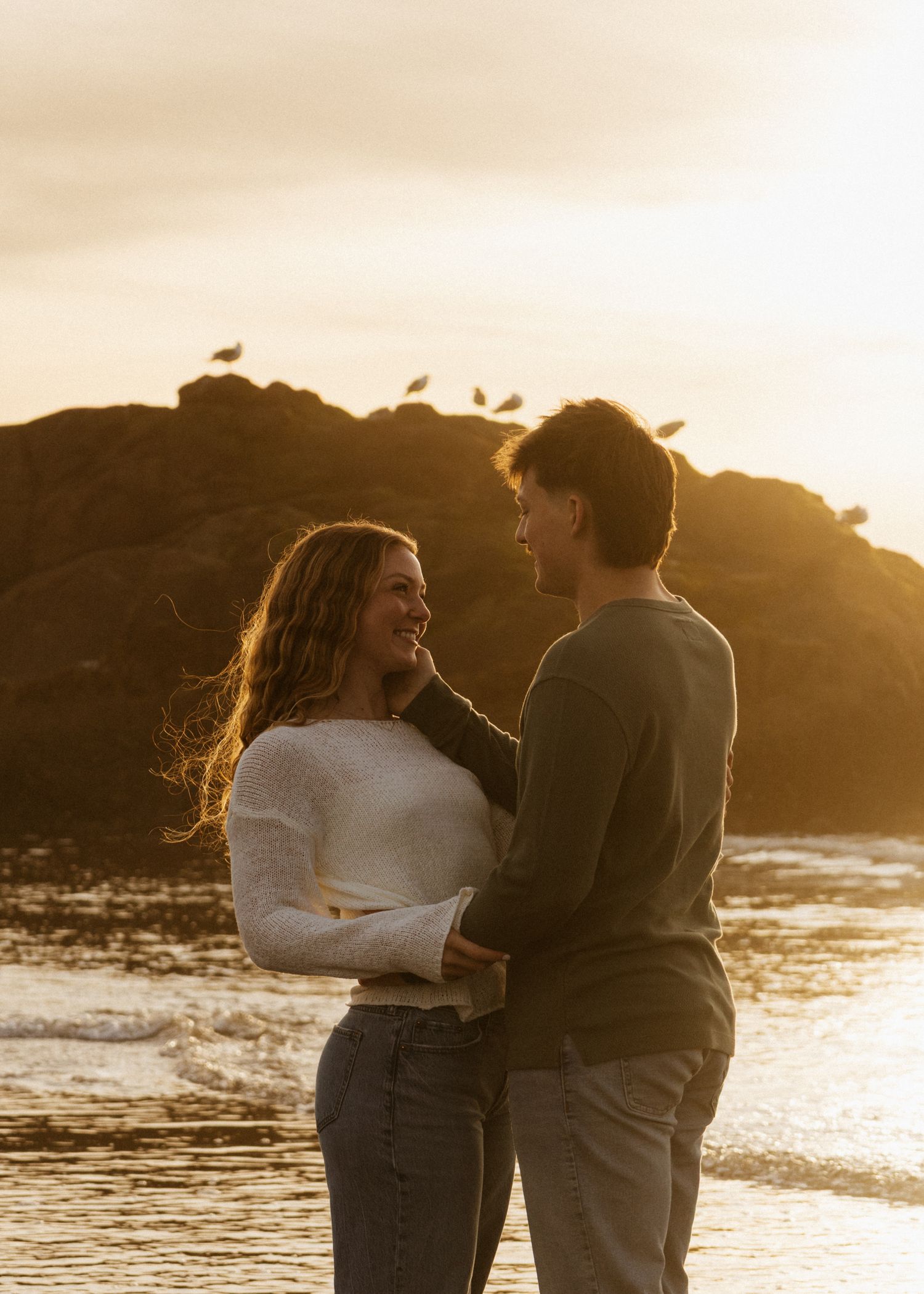Golden hour on the Oregon coast beach with Anna and Carson, holding her face getting ready to bring her in for a kiss.