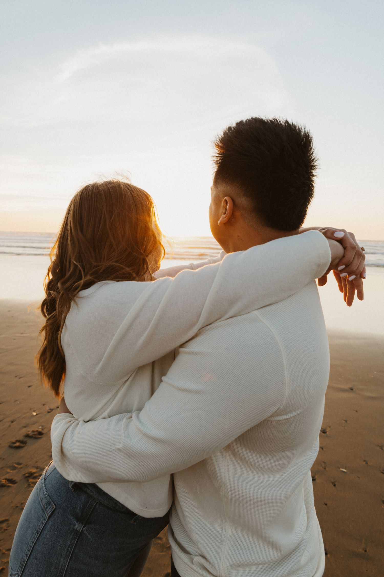 Golden hour Lincoln City, Beach engagement photoshoot couple hugging and admiring beautiful spring sunset on the beach.