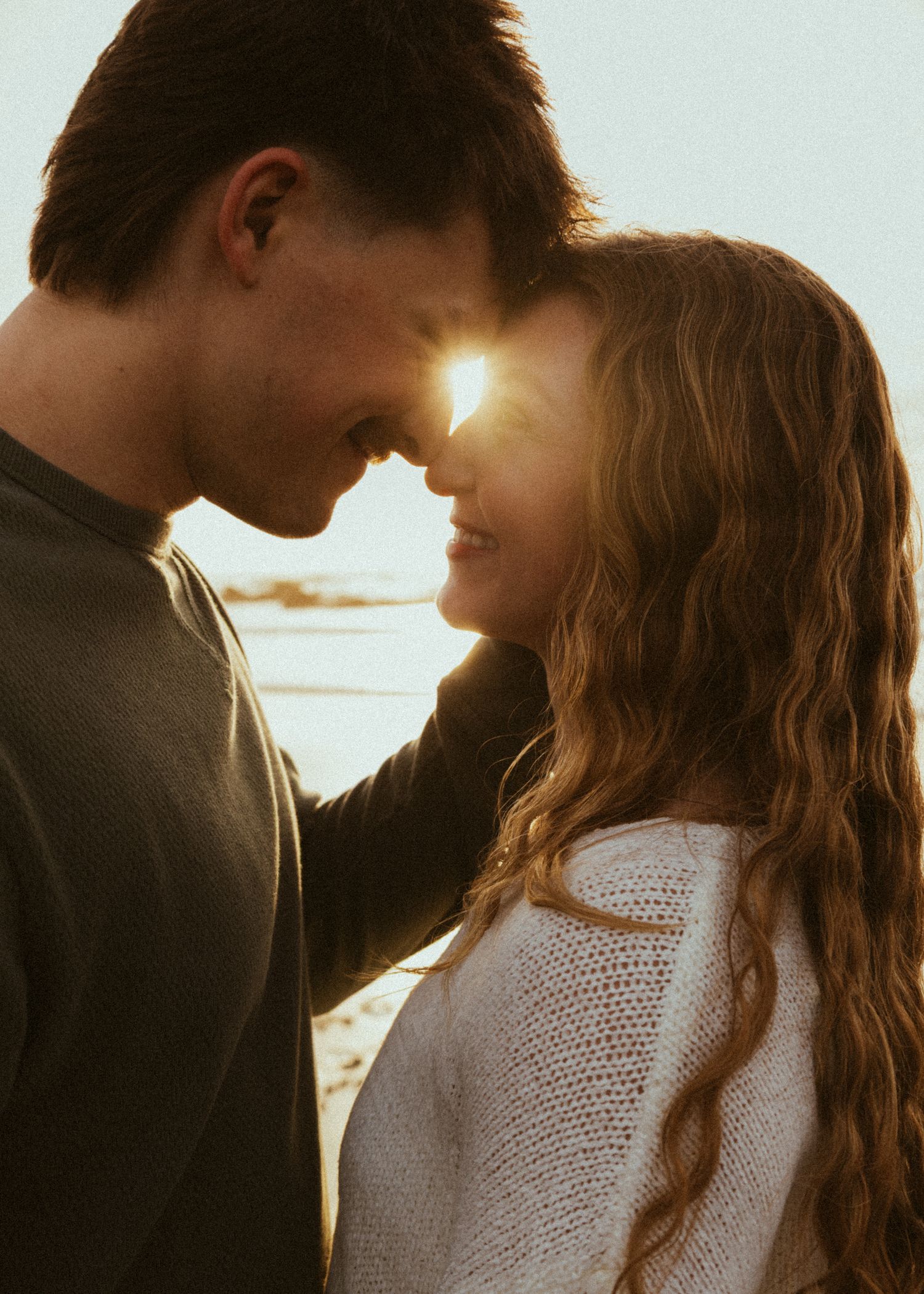 Intimate forehead to forehead couples photoshoot pose on the Oregon Coast during golden hour in April.