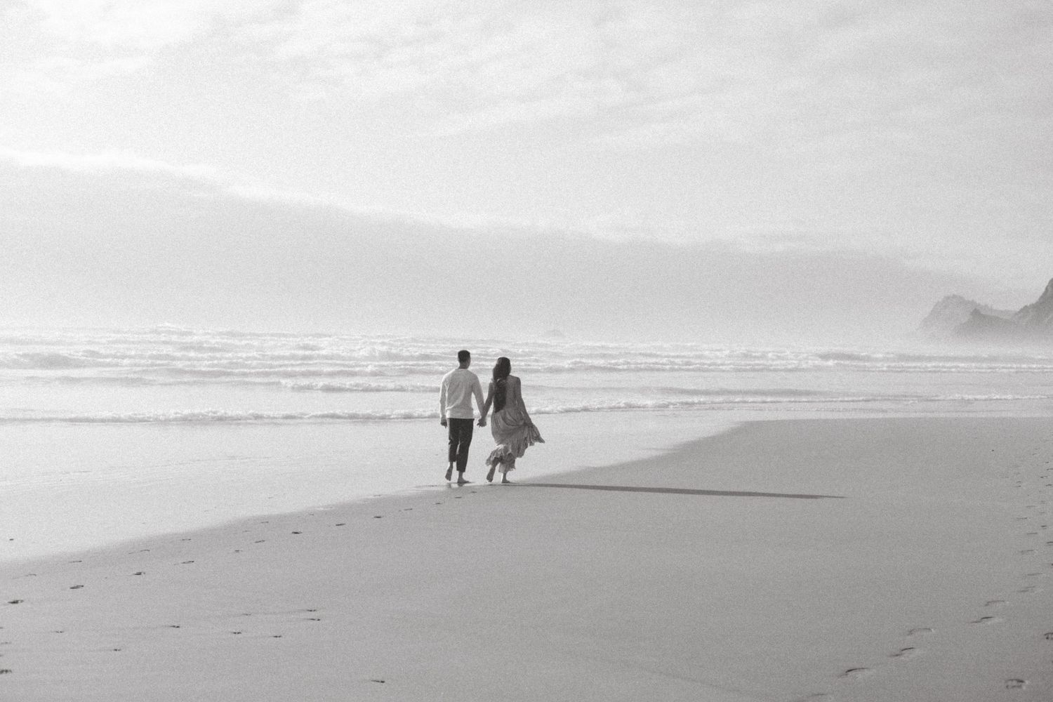 B&W golden hour beach session couple walking down Oregon Coast beach OR