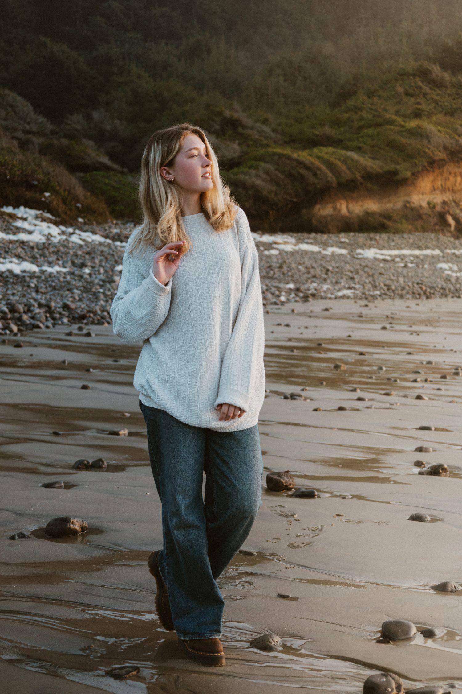 Maddie, PNW Model out of Minnesota walking on Oregon Coast beach messing with her hair looking off into the ocean for fun candid look.