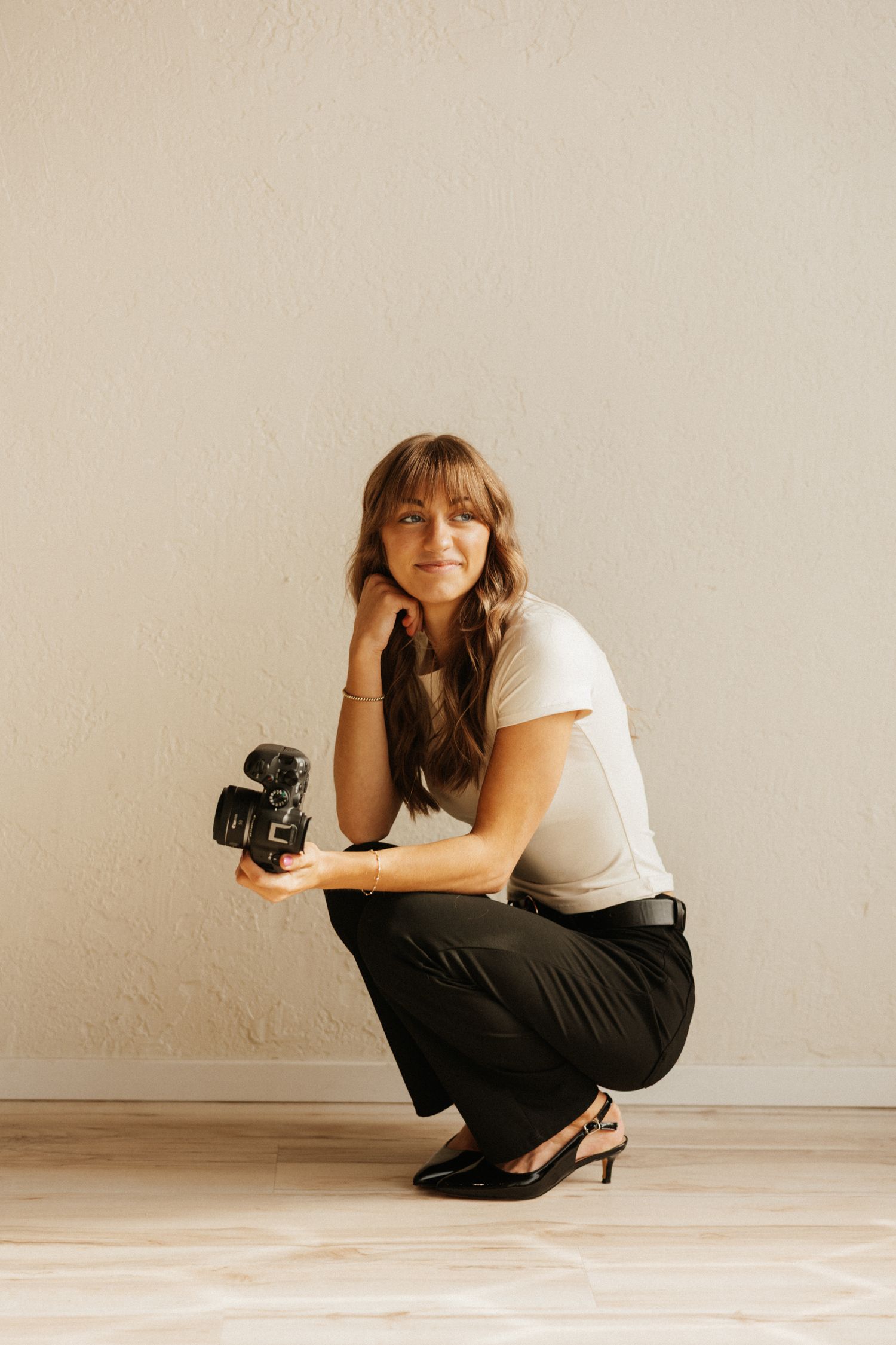 Andi Rane Photo posing with her camera in a bright white studio for branding photos for her photography business