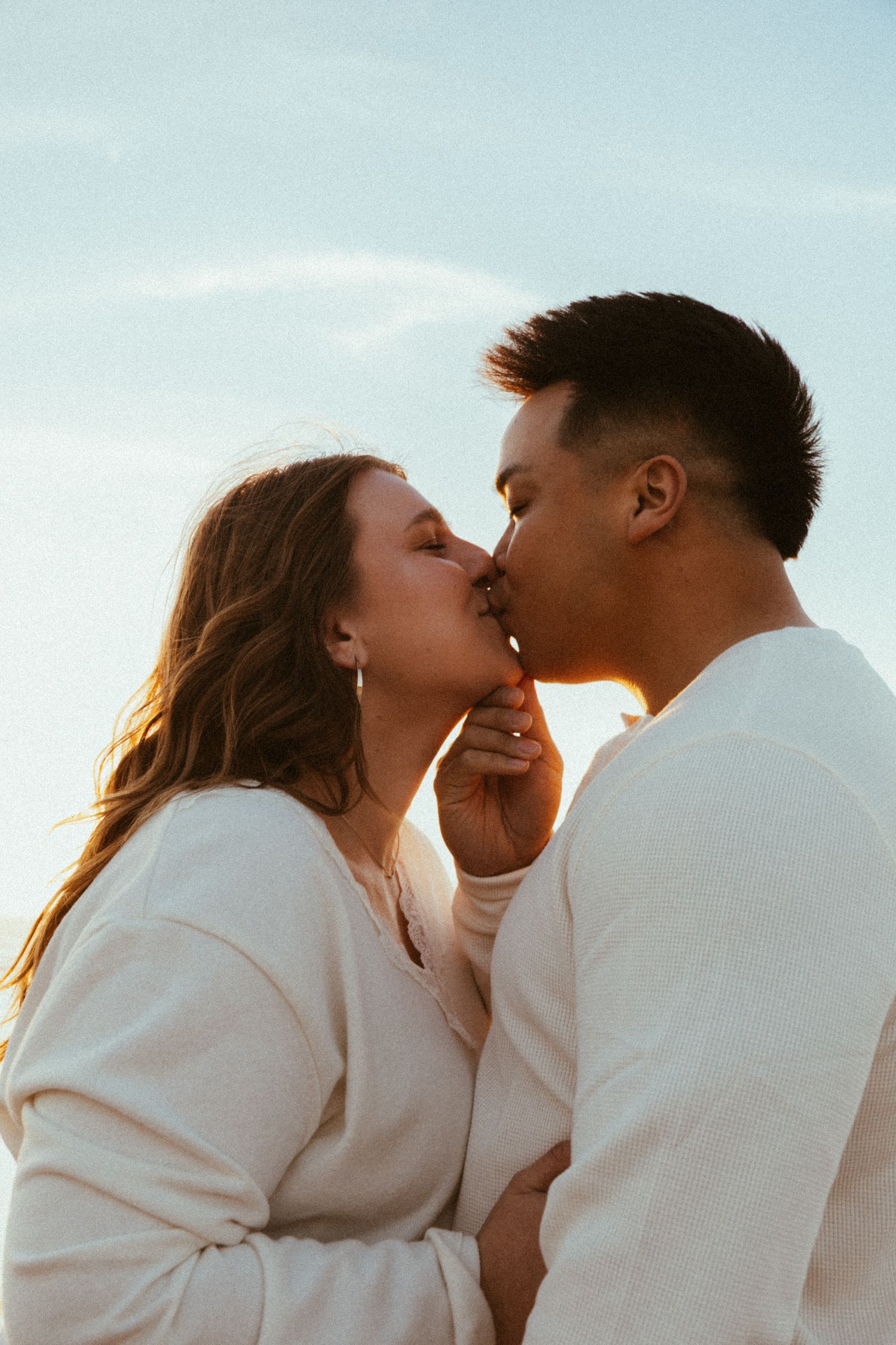 Lincoln City Oregon beach engagement photoshoot with Baylee and Kyle, Kyle pulling her in for an intimate kiss during golden hour.