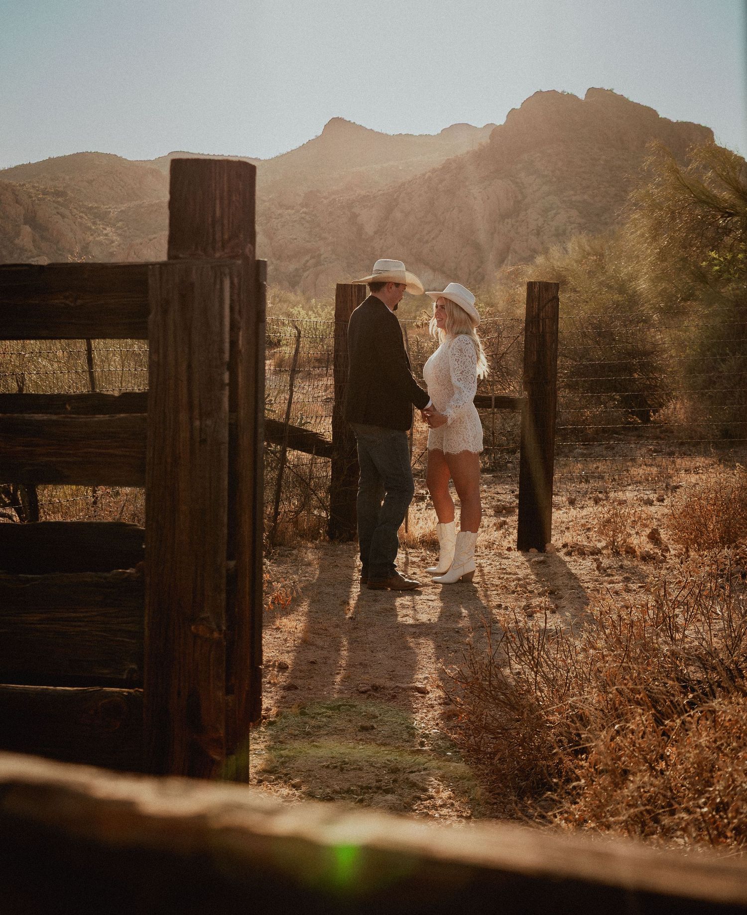 Couple in the Arizona desert with mountains in the background. Couples smiling at each other for their engagement session