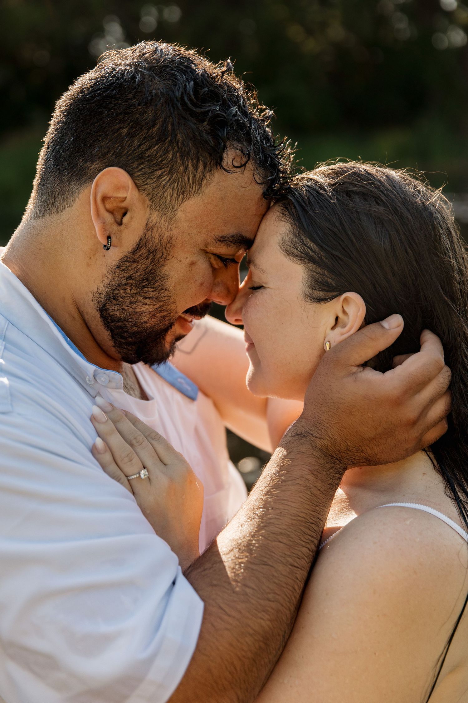Romantic couple sharing an intimate moment outdoors, man tenderly holding woman's face as they lean in close.