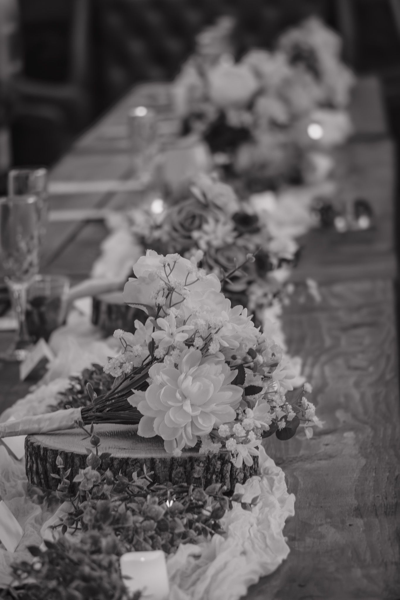 Elegant black and white wedding reception table centerpiece featuring dahlias on rustic wood slice.