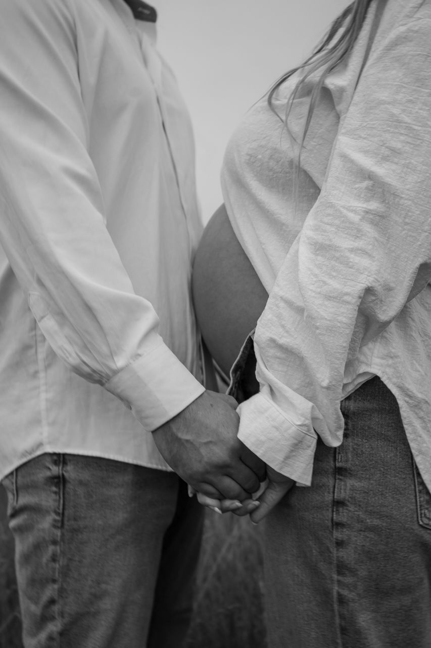 A black and white close-up of a couple holding hands, showing intimate connection.