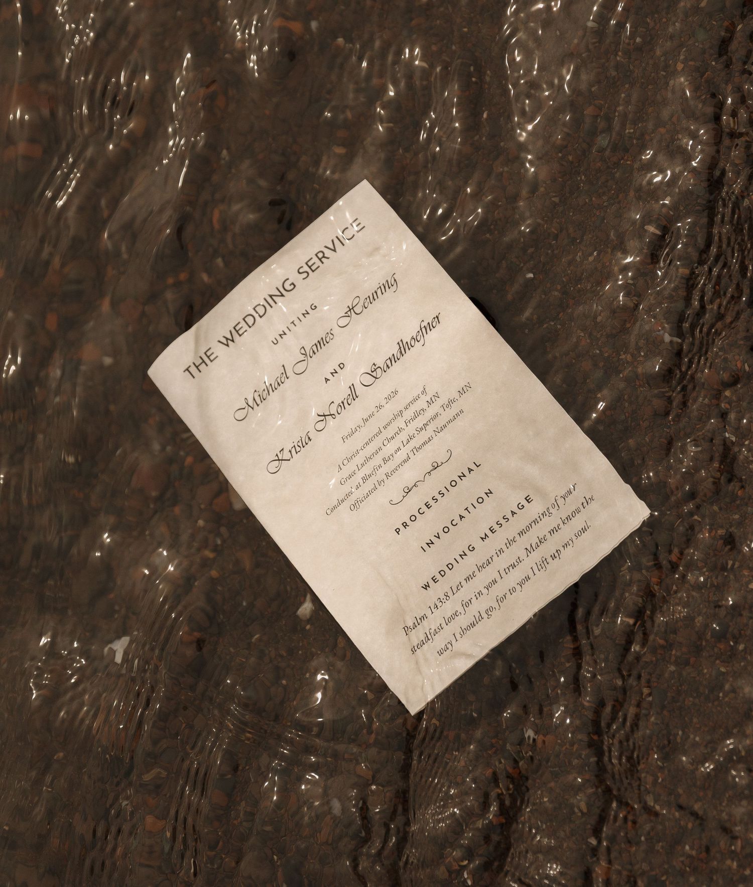 Wedding service program card resting on a dark textured surface, featuring elegant typography for a formal ceremony.