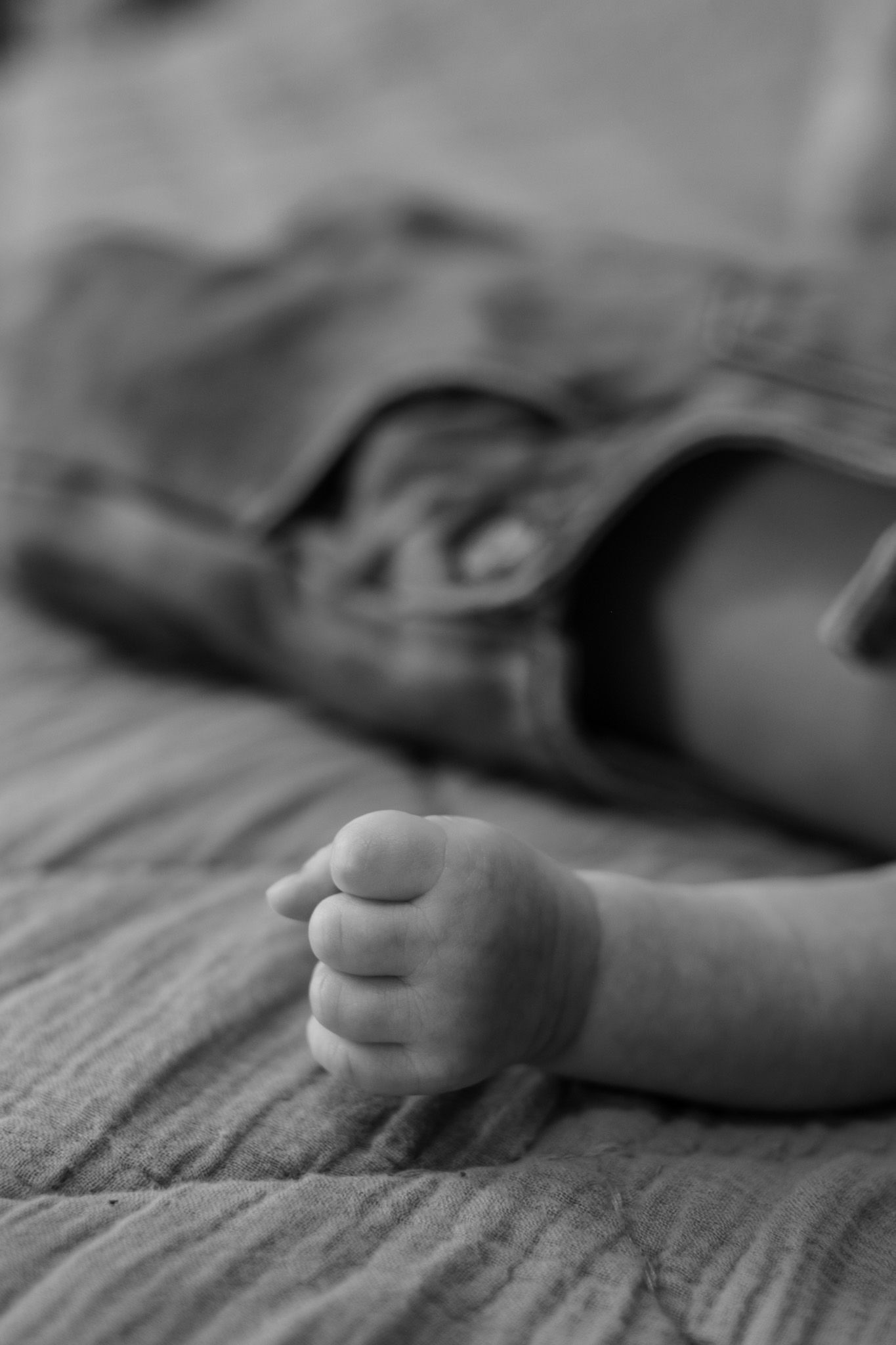 Close-up black and white photograph of hands resting on textured fabric.