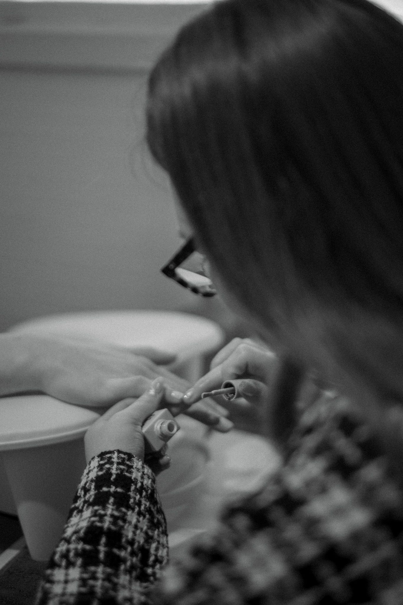 Black and white image of nail care service being performed in professional setting.