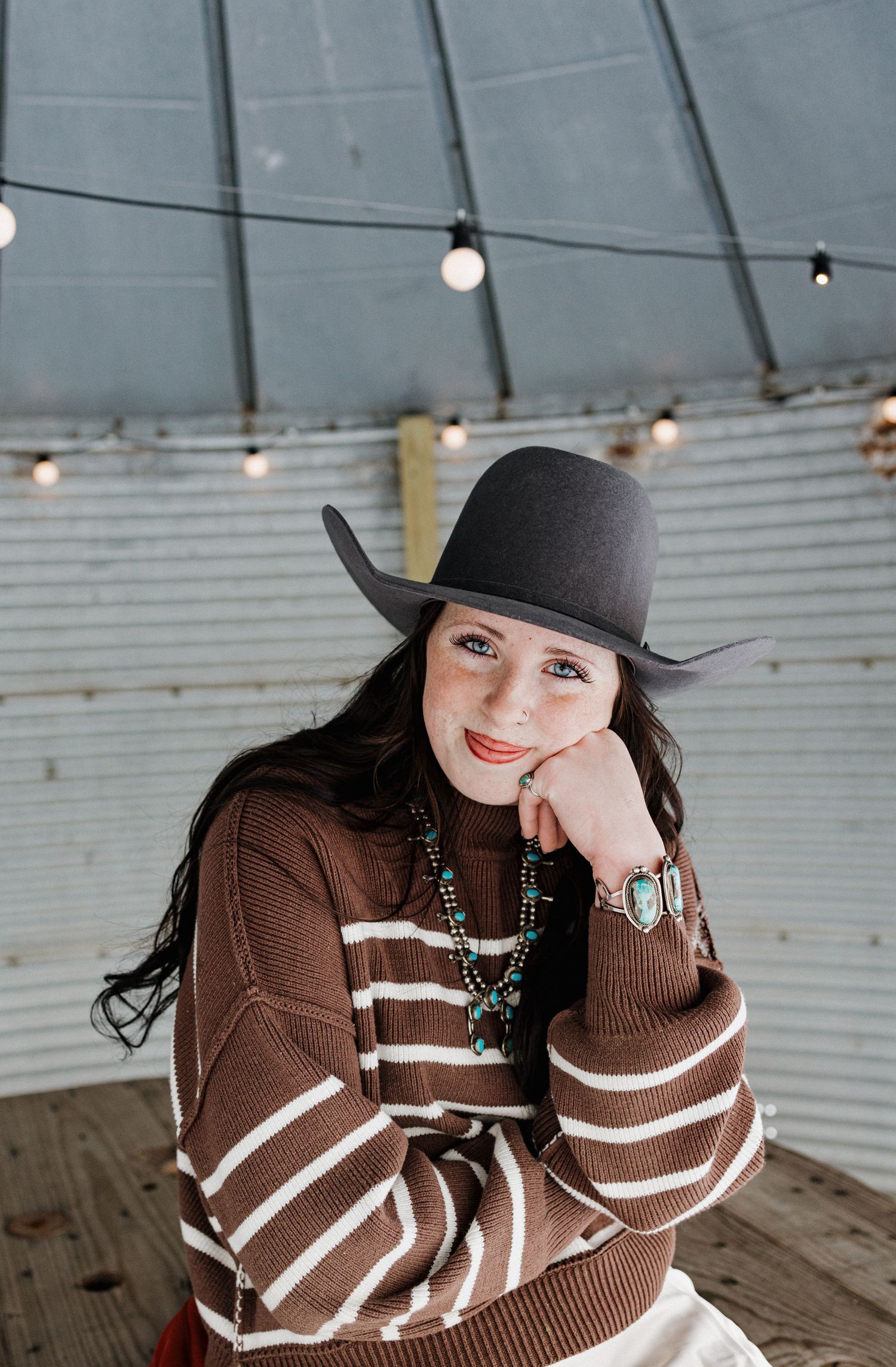 Portrait series of someone wearing a brown striped sweater and black hat in an industrial setting.