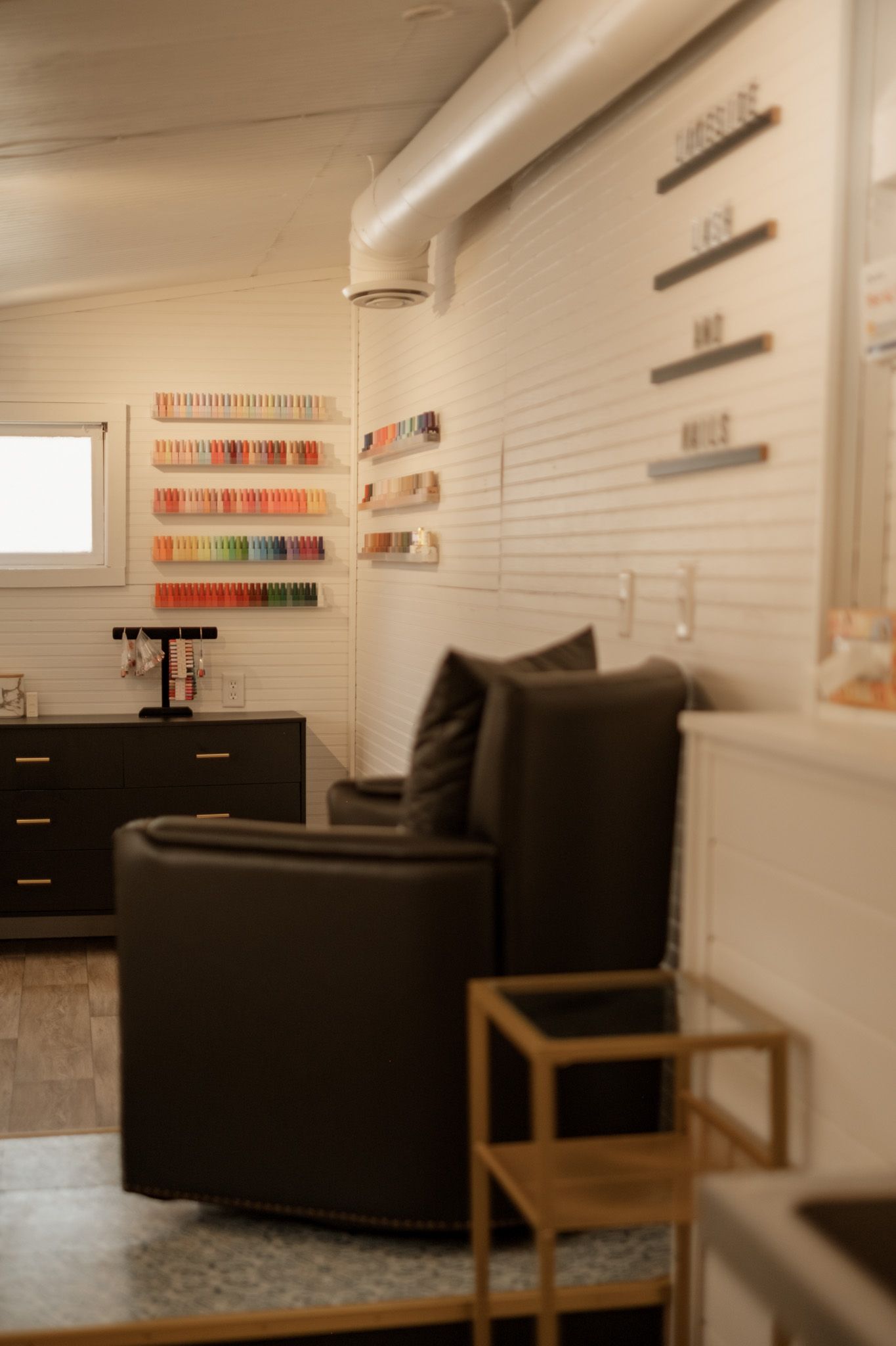 Modern waiting room interior with black couches and decorative wall shelving.