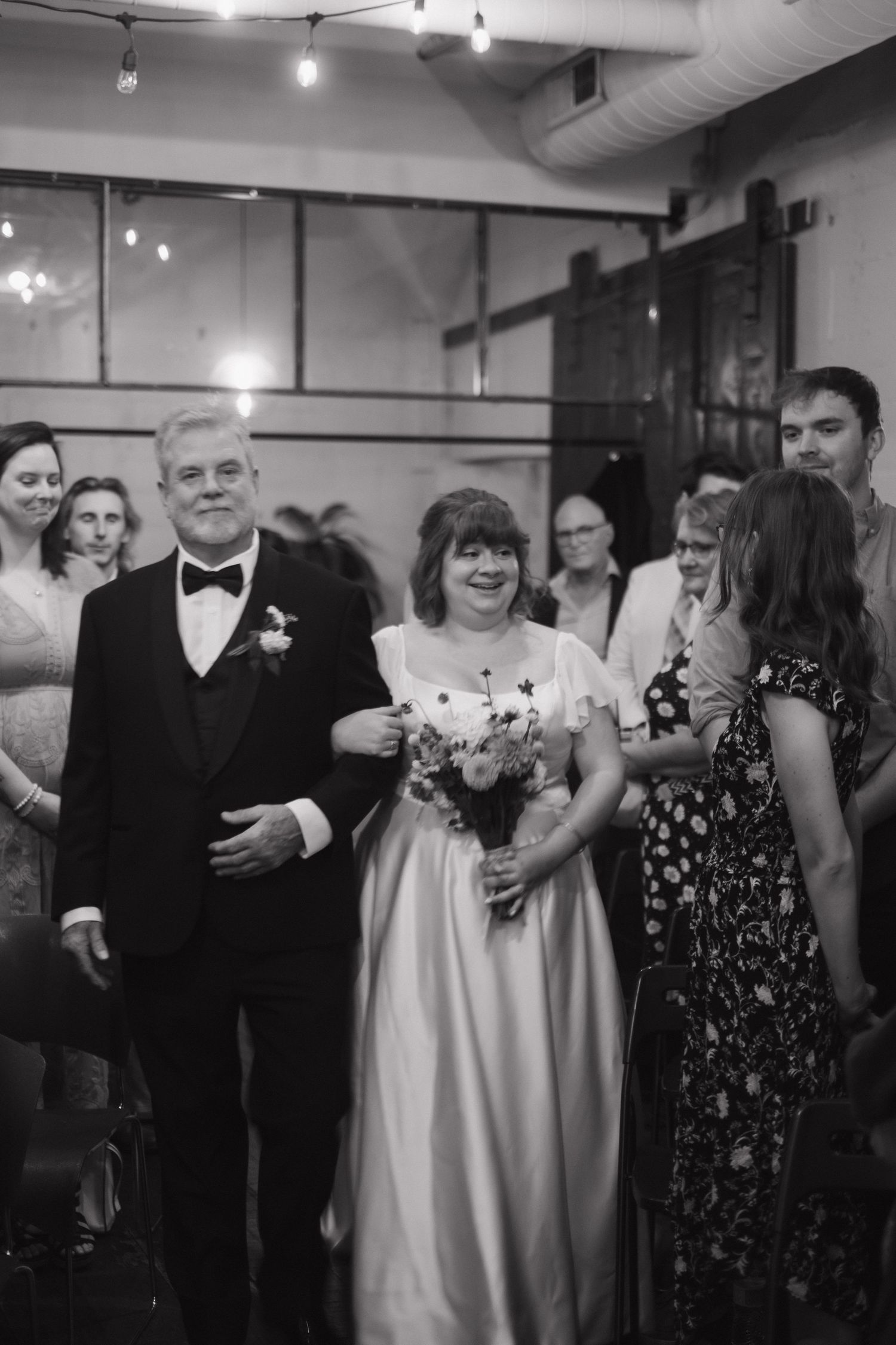 Wedding party gathering indoors wearing formal attire in black and white.