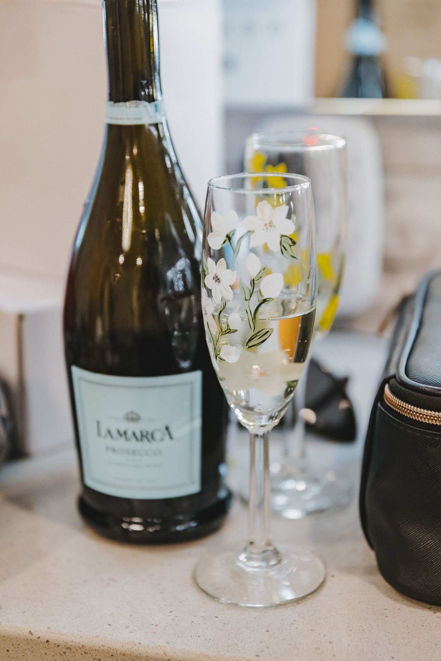 La Marca Prosecco bottle beside a floral champagne flute on a countertop.